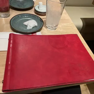 a place setting with a red leather folder