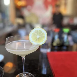 a cocktail in a glass with a slice of lemon