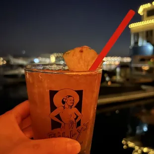 a hand holding a drink with a pineapple garnish