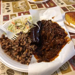 a plate of beans, beans, coleslaw, and pulled pork