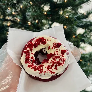 a person holding a red velvet donut