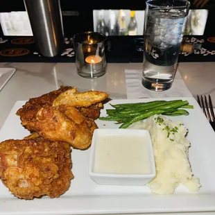 a plate of fried chicken with mashed potatoes and green beans