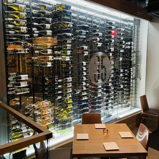 a table and chairs in front of a wine rack