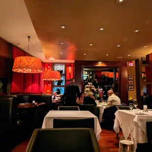 Inside. Dining room. Wide U-shaped booth seating along the perimeter of the main dining room. White tablecloth smaller tables in the center.