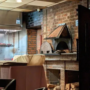 Inside. Brick wood-fired oven with steaks suspended above the grill in the back.