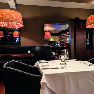 Inside. Dining room. Wide U-shaped booth seating along the perimeter of the main dining room. White tablecloth smaller tables in the center.