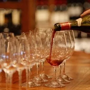 a person pouring wine into wine glasses