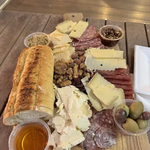 Three different cheeses and meats and olives bread fig jam and spicy mustard