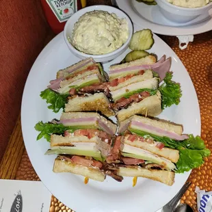 A turkey and bacon club sandwich with potato salad on the side.