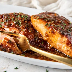 a plate of chicken with sauce and a gold spoon