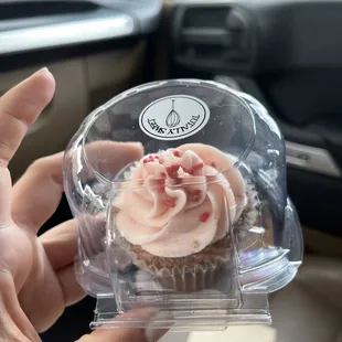 a person holding a cupcake in a clear box