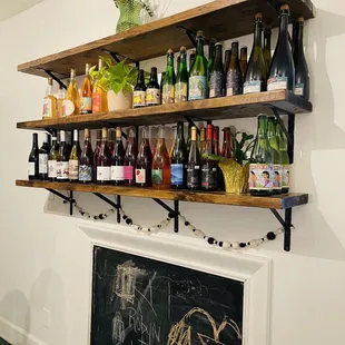 bottles of wine on shelves above a fireplace