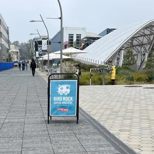 Near the Trolley Station/Bus Stop. Go around the corner of tall black building and it&apos;s a small little shop.