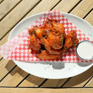 a plate of chicken wings with a side of ranch dressing