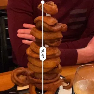 a man sitting at a table with a stack of donuts