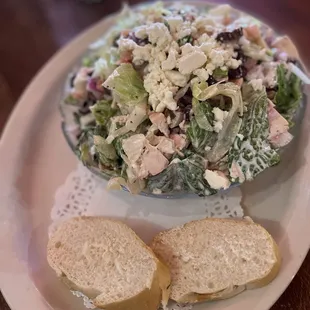 a bowl of salad and two slices of bread on a plate
