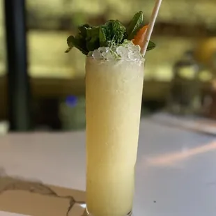 a tall glass of cocktail with a straw and garnish