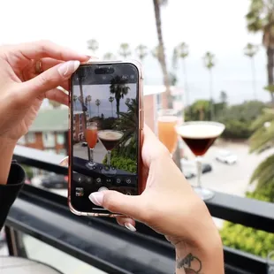 a person taking a picture of a glass of wine