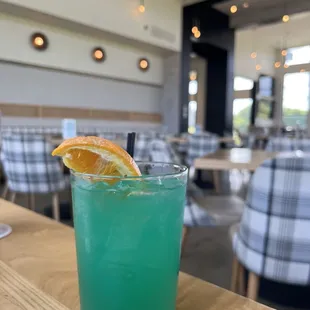 a blue cocktail with orange slice