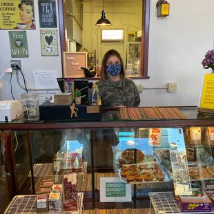 a woman taking a selfie in front of a bakery counter