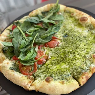 a pizza with spinach and tomatoes