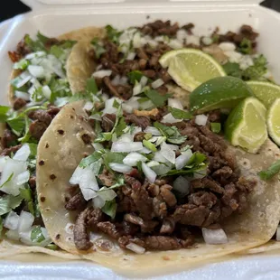 Carne asada tacos in flour tortilla topped off onion and cilantro