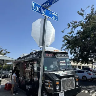 Front view of taco truck and street signs.