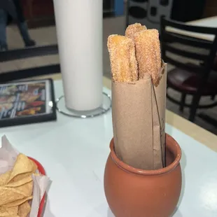 churros in a clay pot and a glass of milk