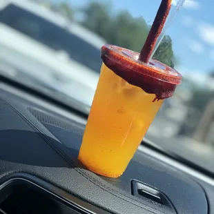 a drink in a plastic cup on the dashboard of a car