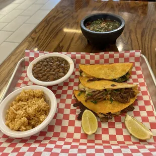 Quesabirria tacos with rice and beans and a small side of consume.