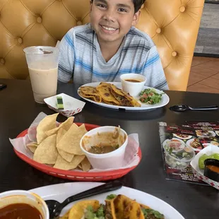 a boy sitting at a table with plates of food