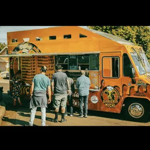 a group of people standing in front of a food truck