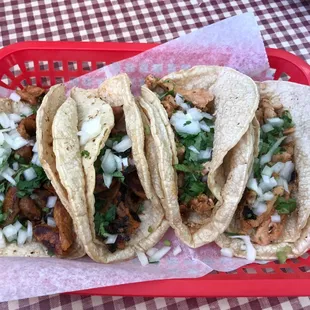Two pastor tacos on the left, and two chicken tacos on the right.