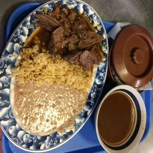 Platillo de birria servida con arroz y frijoles y su consomé !