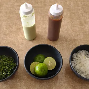 Salsa bottles, cilantro, limes, and diced white onions