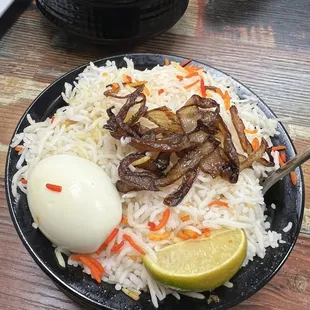 a plate of biryani with rice and an egg