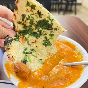 a hand holding a piece of naan bread