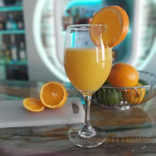 a glass of orange juice and a bowl of oranges