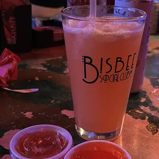 a glass of beer and two small bowls of ketchup