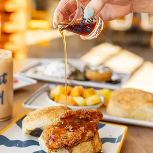 a person pouring syrup on a biscuit