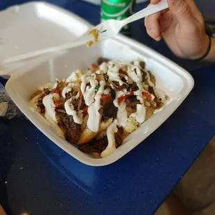 a hand holding a fork over a plate of food