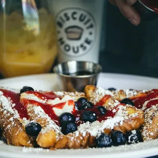 a plate of french toast with berries and powdered sugar
