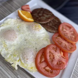 Triple egg and sausage patties plated with tomatoes.