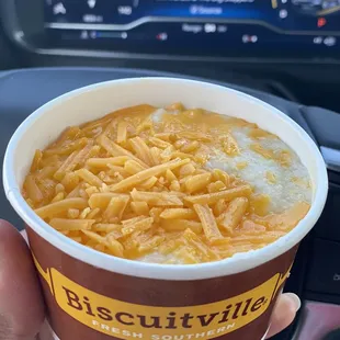 a person holding a cup of macaroni and cheese