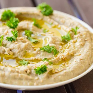 a plate of hummusl with olive oil and parsley