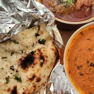 Butter chicken and garlic naan and tilapia curry pictured on top.