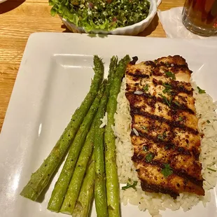 Grilled salmon on a bed of rice with sides of tabouli and asparagus