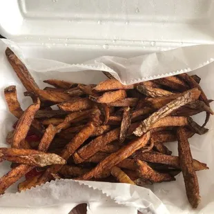 a hand holding a box of fries
