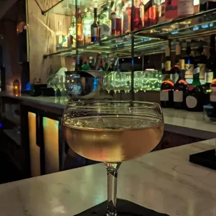 a glass of wine sitting on a bar