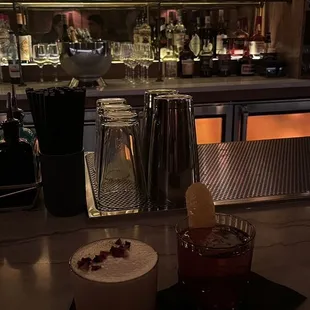 a glass of alcohol and a cocktail on a bar counter